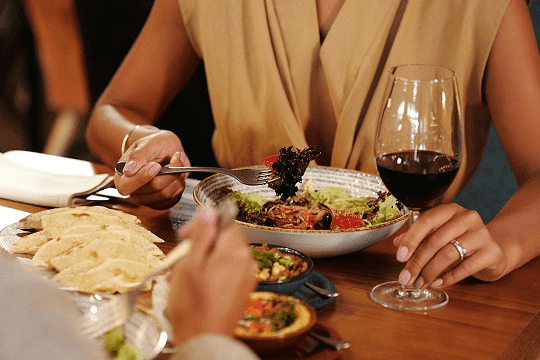 Une femme boit un verre de vin rouge en accord avec son plat Une femme boit un verre de vin rouge en accord avec son plat